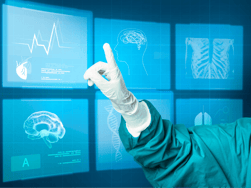 A doctor's hand in a surgical glove and gown is pointing at a digital scan of a patient